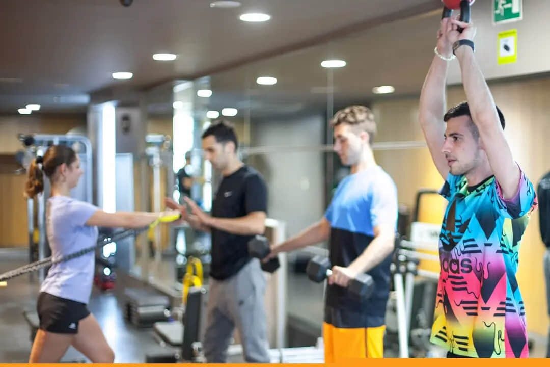 Entrenador personal corrige a una clienta durante un remo con polea en nuestro estudio de Barcelona