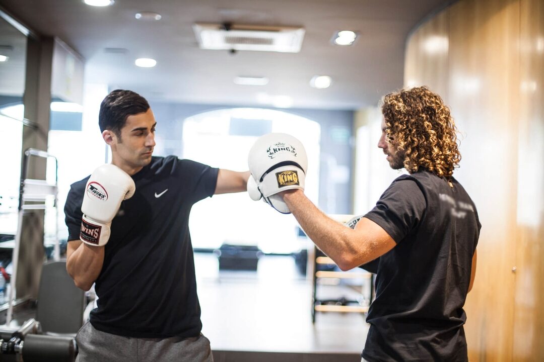 Sesión privada de boxeo: el entrenador sostiene las manoplas mientras el alumno conecta un directo en nuestro estudio de Barcelona